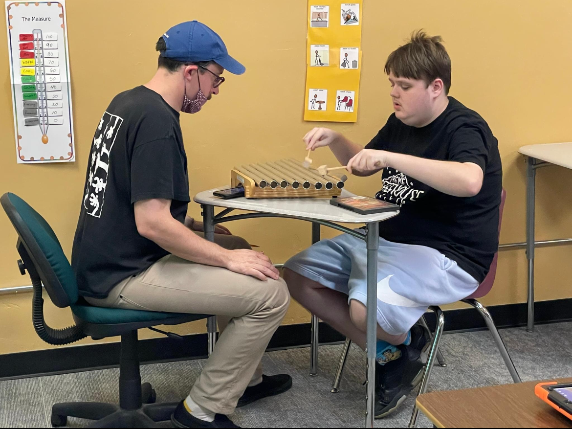 A photo of Maximo working with a client in a music therapy session playing metal tone bars.
